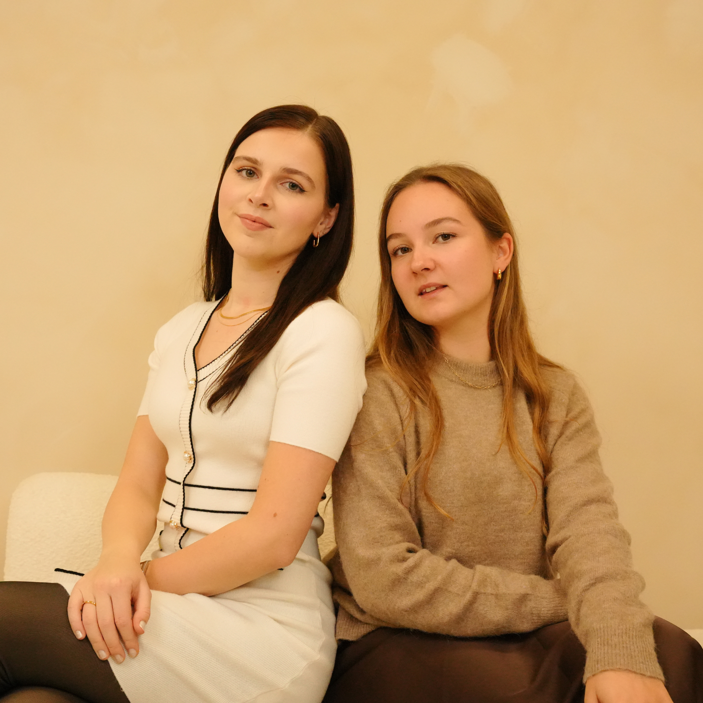 Gold necklace with sleek layers, alongside two women in casual clothing.