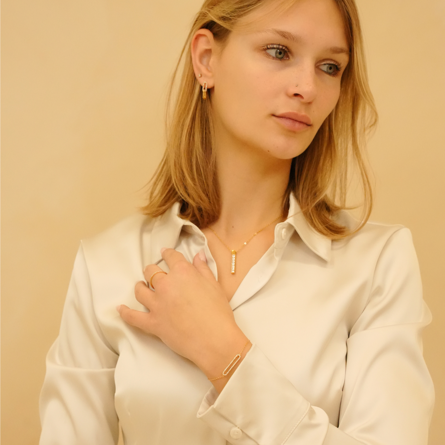 Dainty gold zirconia earrings with cubic detail, styled with matching ring, bracelet and pendant necklace.