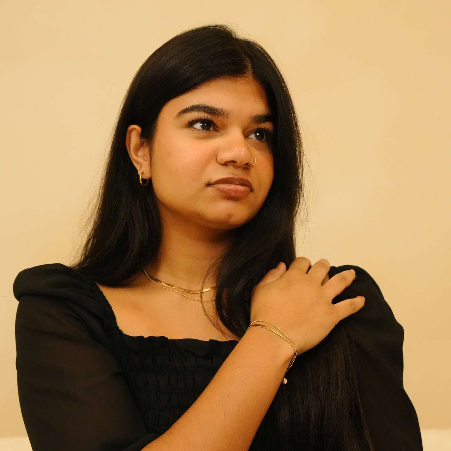Sleek layers necklace featuring a gold chain, with model wearing a black top and gold jewelry.
