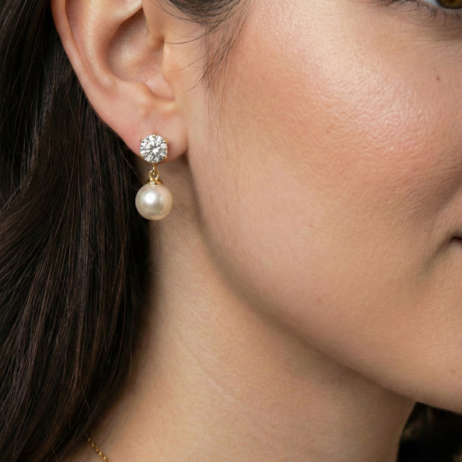 Close-up of a woman wearing pearl earrings with a gold and diamond accent.