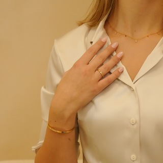 Gold necklace with sparkle drops, accented with gold ring and bracelet.