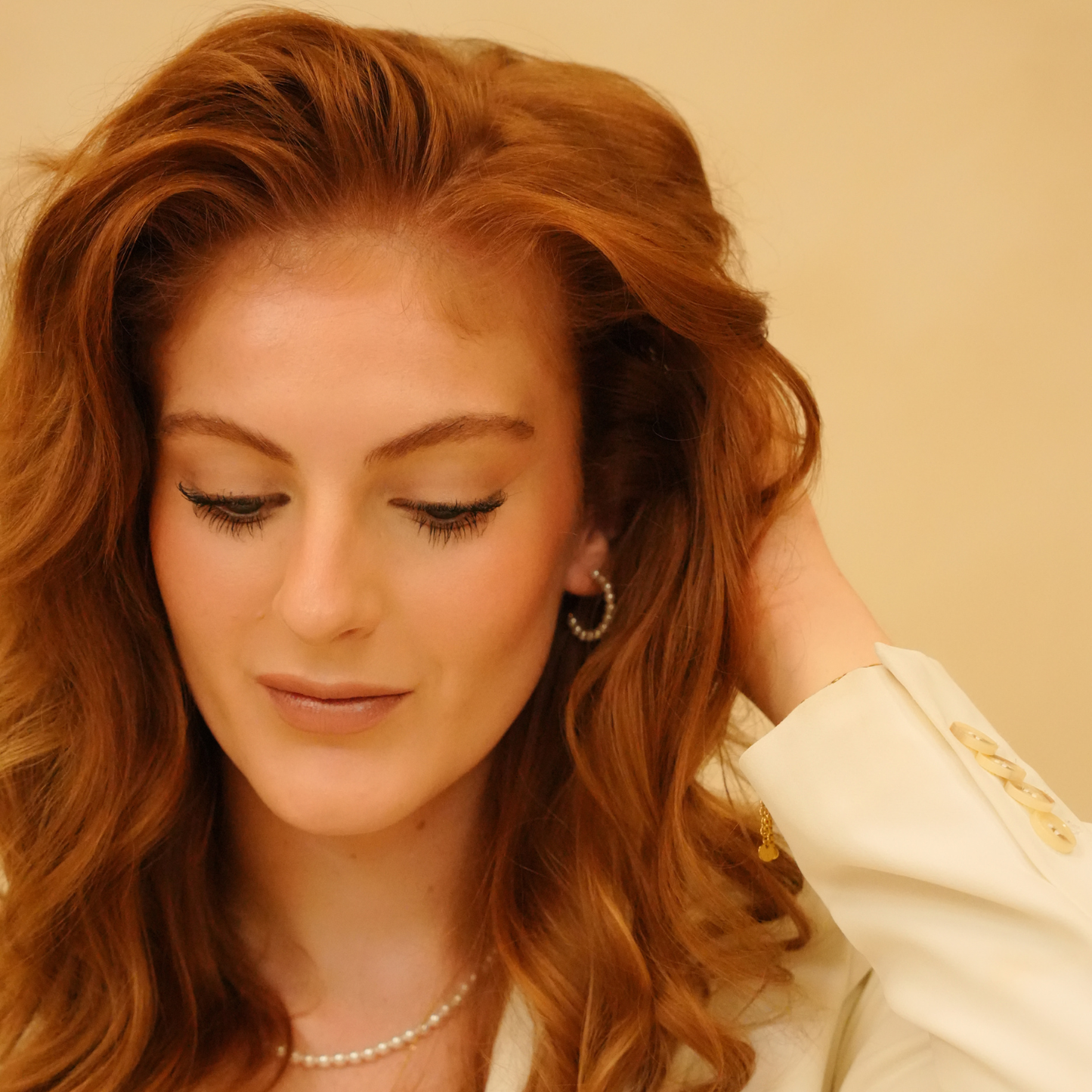 Pearl hoop earrings with pearls, worn with a pearl necklace and white blazer.