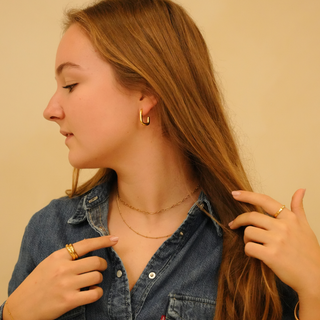 Fine beaded necklace with gold chain, worn with gold earrings and rings.