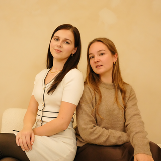 Gold necklace with sleek layers, alongside two women in casual clothing.