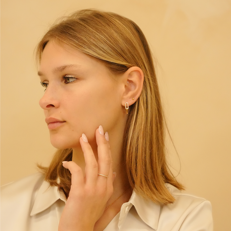 Dainty zirconia earrings with a delicate glow, styled with a golden ball stud, shown on a model.