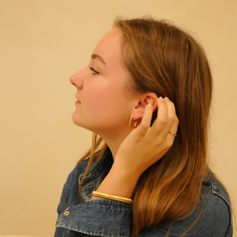 Gold flexible bracelet with corrugated texture, worn with a denim jacket and ring.